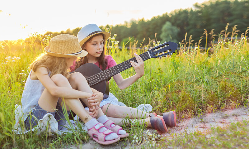 Kinder spielen im Gras Gitarre
