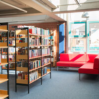 Rotes Sofa und Bücherregale in der Leseecke der Stadtbücherei Hürth.