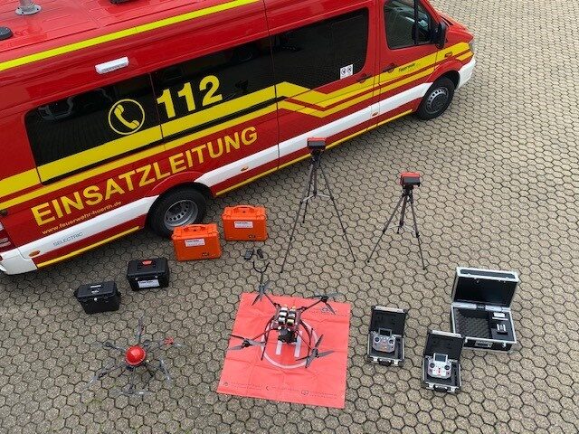 Eine Drohne samt Ausrüstung aufgebaut vor einem Feuerwehr Einsatzwagen der Stadt Hürth.