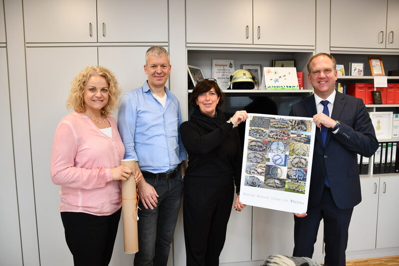 Schulleiterin Jennifer Juncker, Schulleiter Thorsten Jürgensen-Engl und Monika Sahre überreichten Bürgermeister Dirk Breuer (v.l.n.r.) ein frisch gedrucktes Plakat.