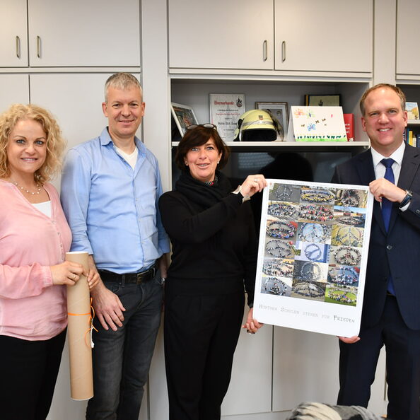 Schulleiterin Jennifer Juncker, Schulleiter Thorsten Jürgensen-Engl und Monika Sahre überreichten Bürgermeister Dirk Breuer (v.l.n.r.) ein frisch gedrucktes Plakat.