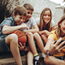 Group of kids having fun taking a selfie using mobile phone. Happy boys and girls sitting on the edge of a street taking a selfie.