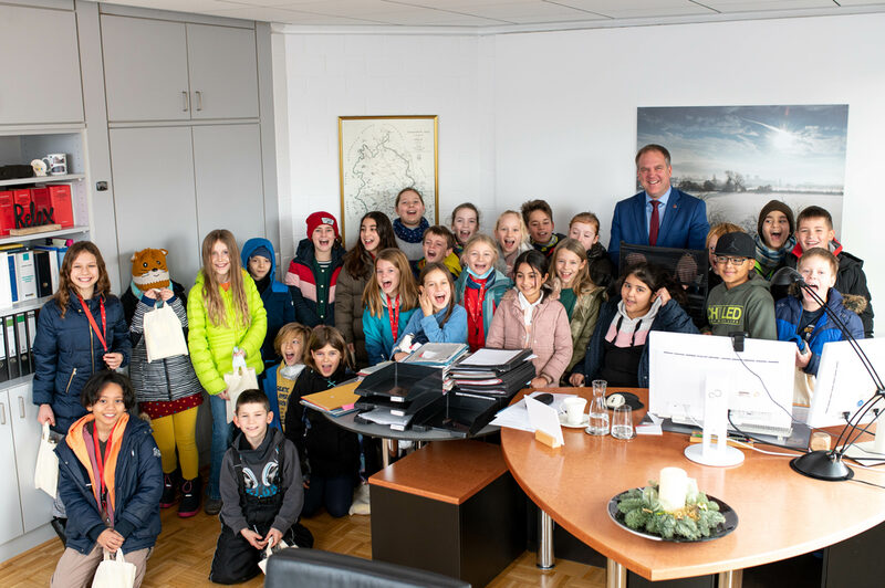 Die Schülerinnen und Schüler der Igelklasse auf einem Gruppenfoto mit Bürgermeister Dirk Breuer, nachdem sie das Büro genau inspiziert haben.